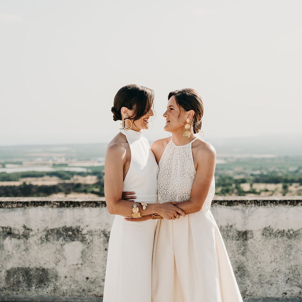 brides embracing looking over italian vineyard