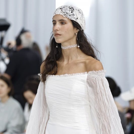 Andrea Lalanza draped off-the-shoulder wedding dress with sheer sleeves and lace headwear at Barcelona Bridal Fashion Week 2026