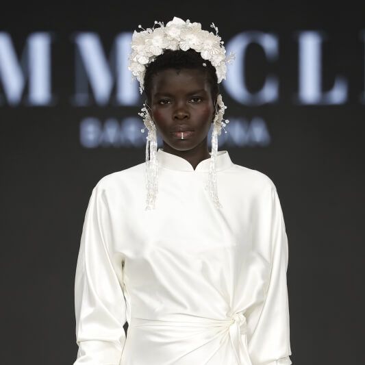 Immaclé satin wedding dress with high neckline and floral headpiece on the runway at Barcelona Bridal Fashion Week 2026
