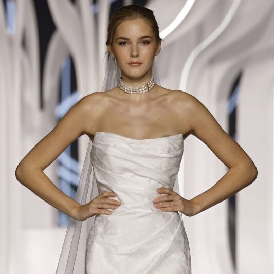 Justin Alexander strapless satin mermaid wedding dress with pearl choker and veil at Barcelona Bridal Fashion Week 2026