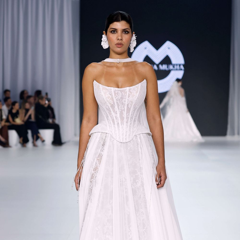 Oksana Mukha corset wedding dress with lace skirt and statement floral earrings at Barcelona Bridal Fashion Week 2026