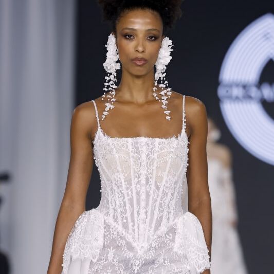 Oksana Mukha lace wedding dress with corset bodice and statement floral earrings on the runway at Barcelona Bridal Fashion Week 2026