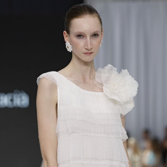 Olga Macia layered sheer wedding dress with ruffle tiers and oversized floral shoulder detail at Barcelona Bridal Fashion Week 2026