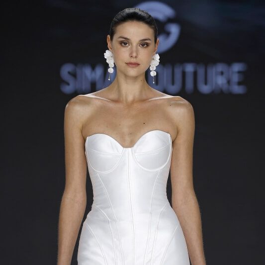 Sima Couture strapless corset wedding dress with floral hem and statement earrings at Barcelona Bridal Fashion Week 2026
