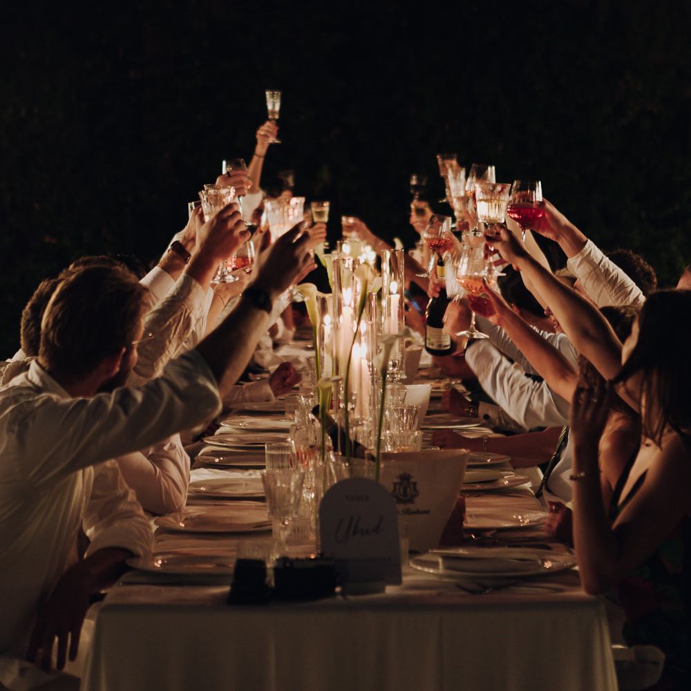 candlelit dinner cheers guests long table night reception