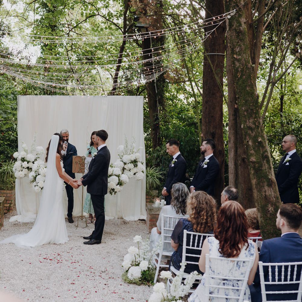 outdoor woodland wedding ceremony white draping fairy lights
