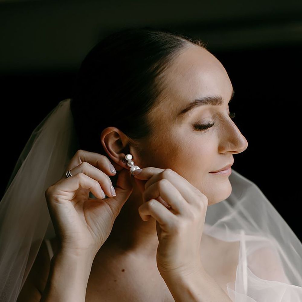 Bride putting on pearl wedding earrings