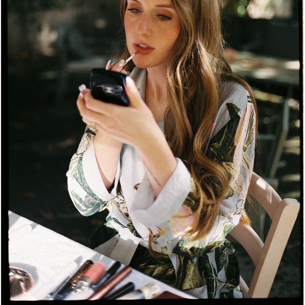 bride in silk gown applying lipstick