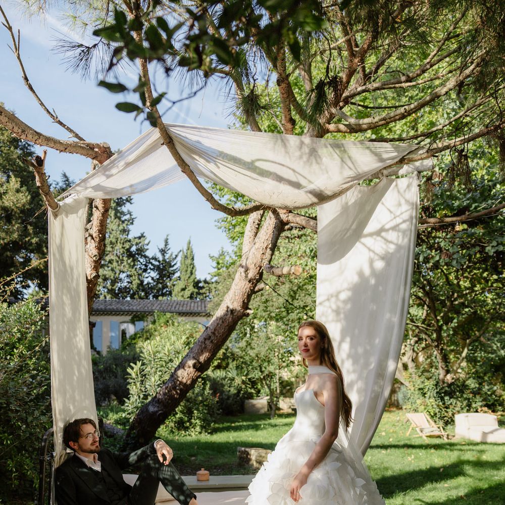 couple pose under fabric decor wooded area