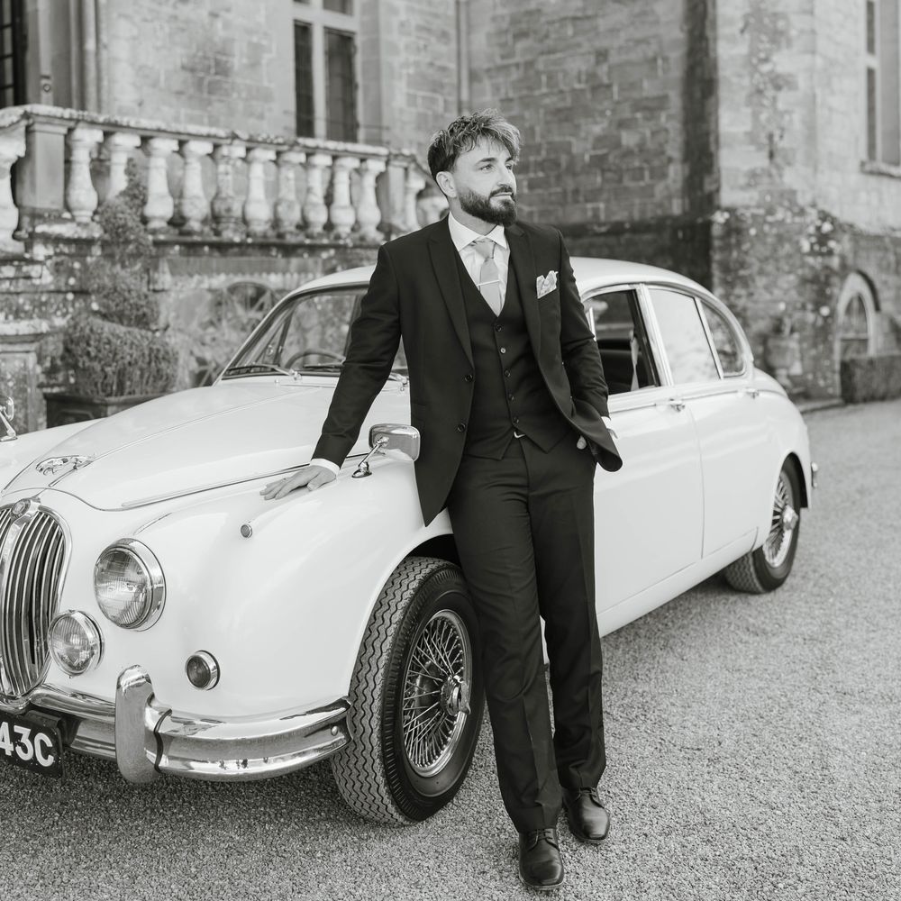 groom posing classic white vintage wedding car