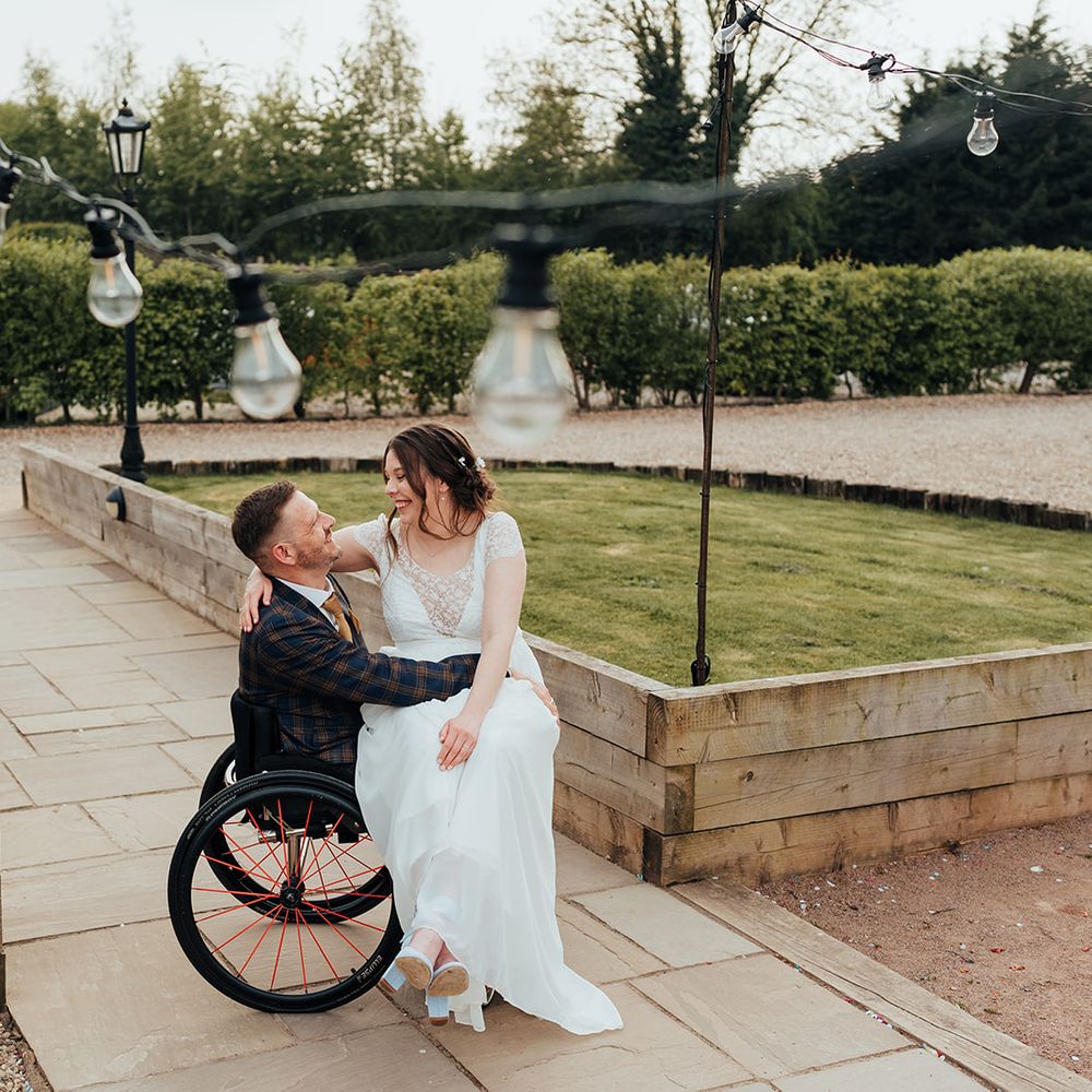 bride on grooms lap under bulb fairy lights