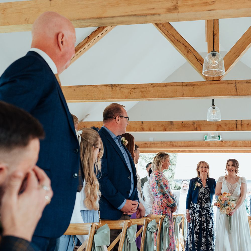 bride walking down aisle groom wipes tears
