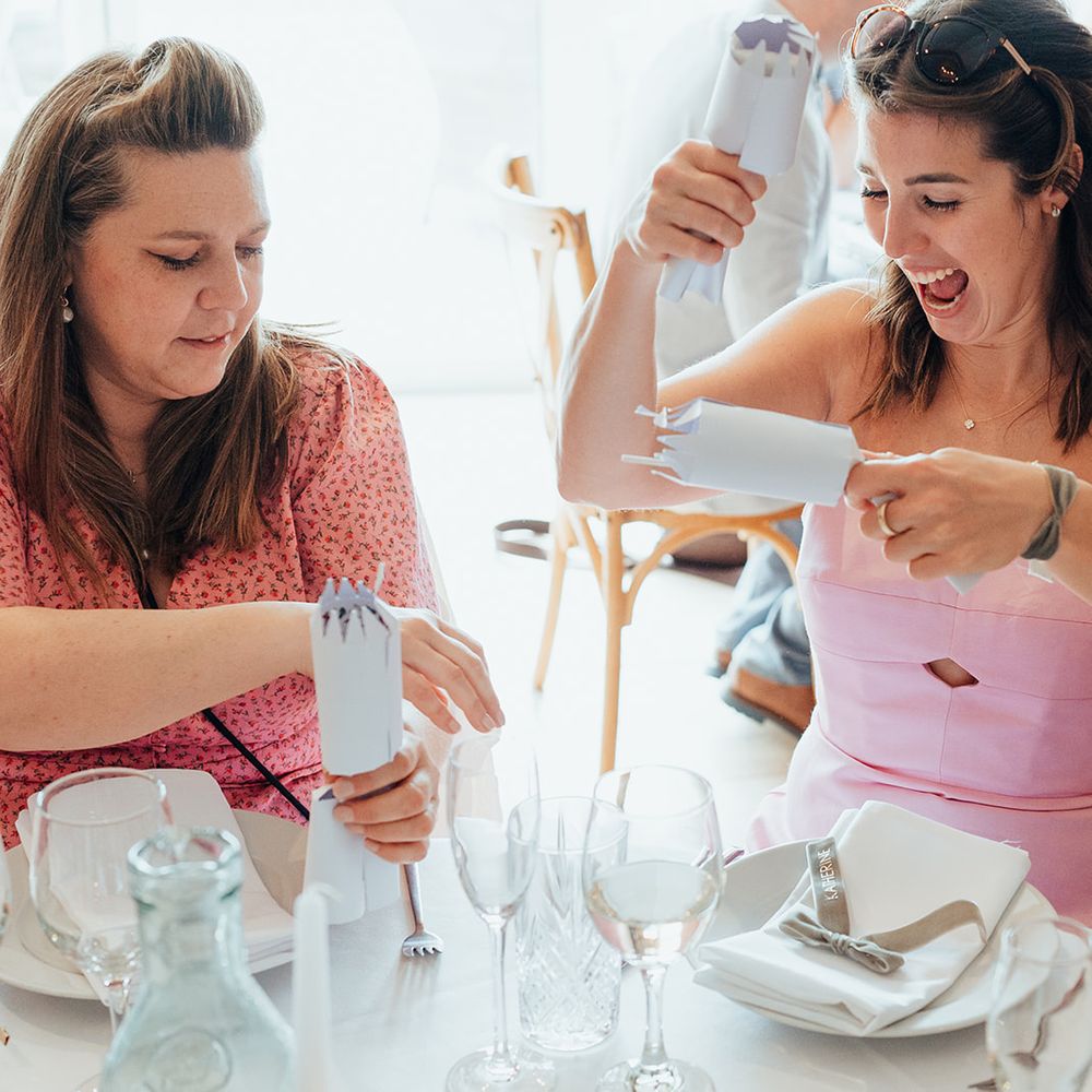 guests laughing using white wedding crackers