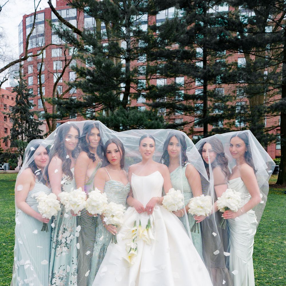 bridesmaids pose under brides floral veil