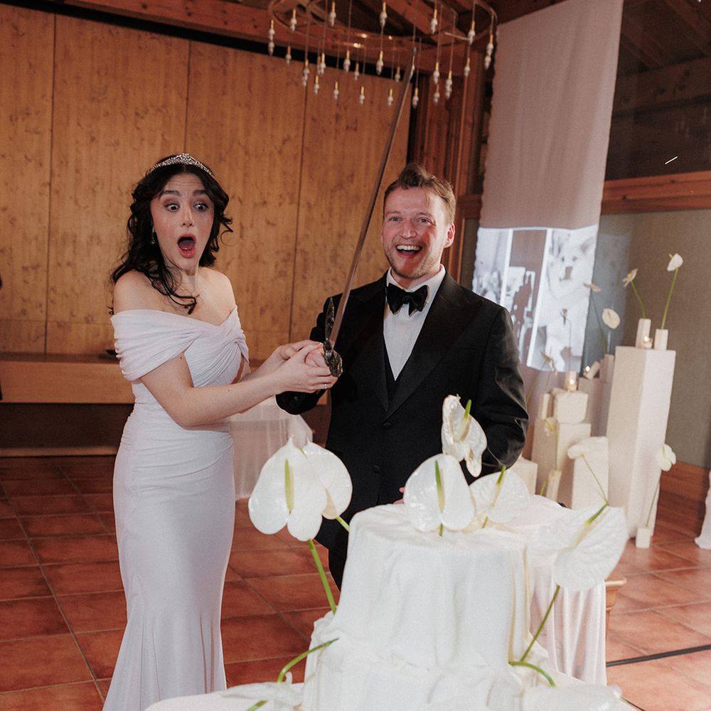 white wedding cake cutting with anthurium flowers