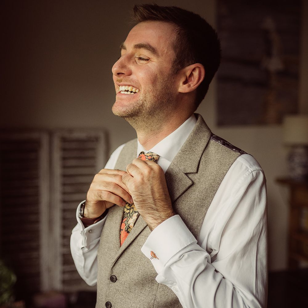 groom smiling putting on tie
