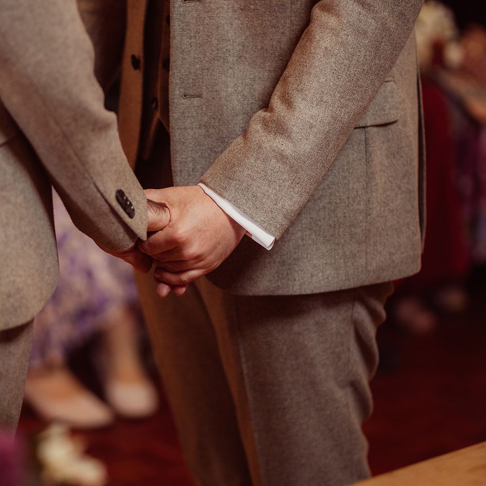 grooms holding hands matching grey suits