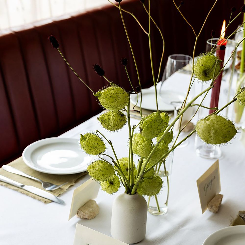 White bud vases with green florals and blooms with place names