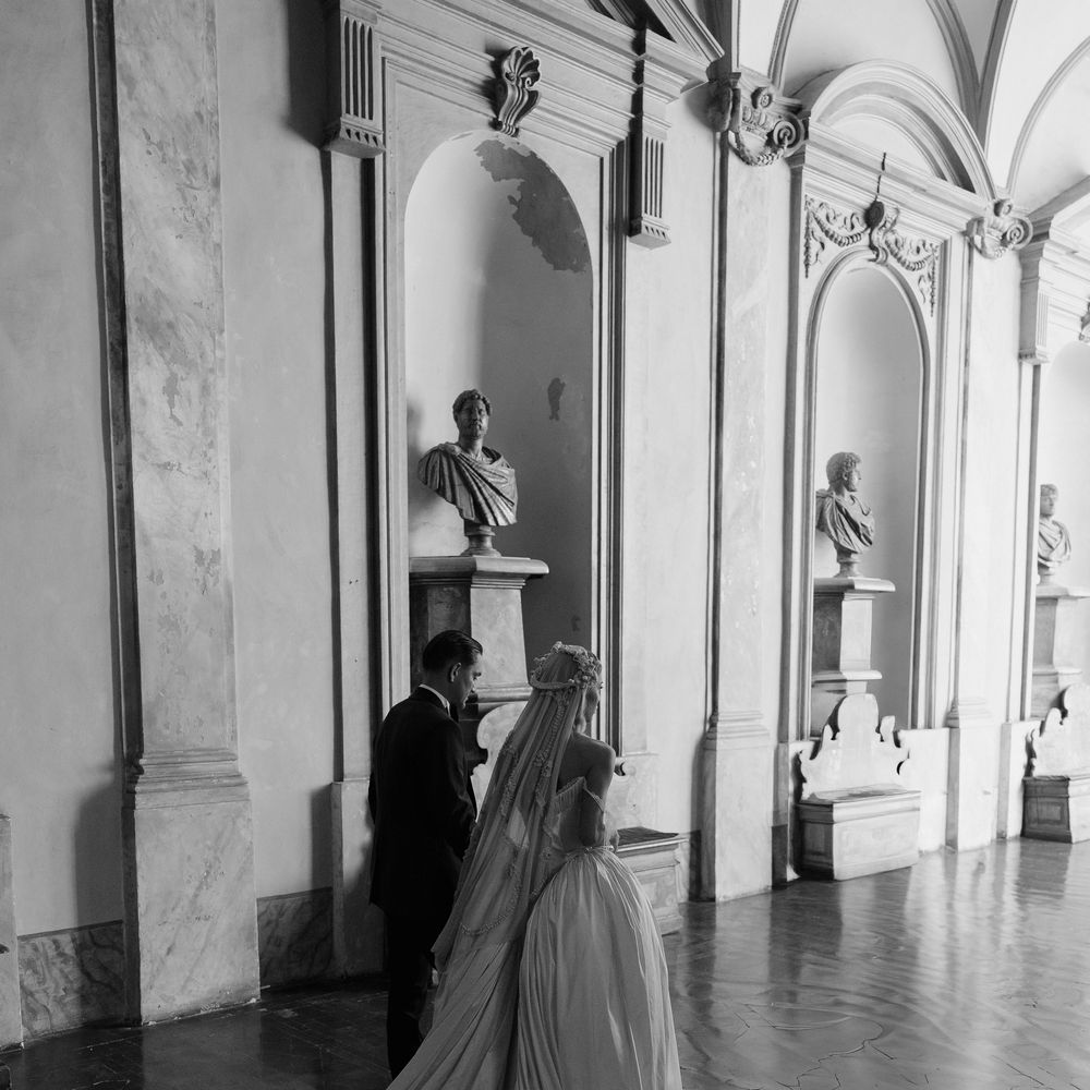 couture wedding gown long train walking through castle hallways