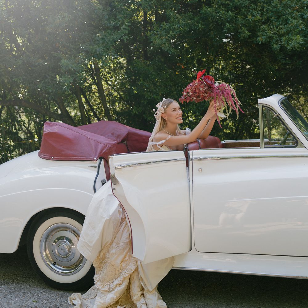 cream and red vintage car bride smiling with bouquet
