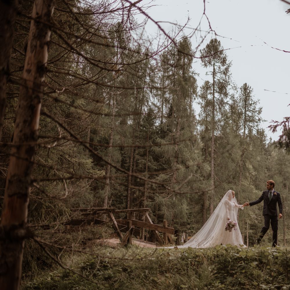 bride and groom holding hands walking through wooded area forest