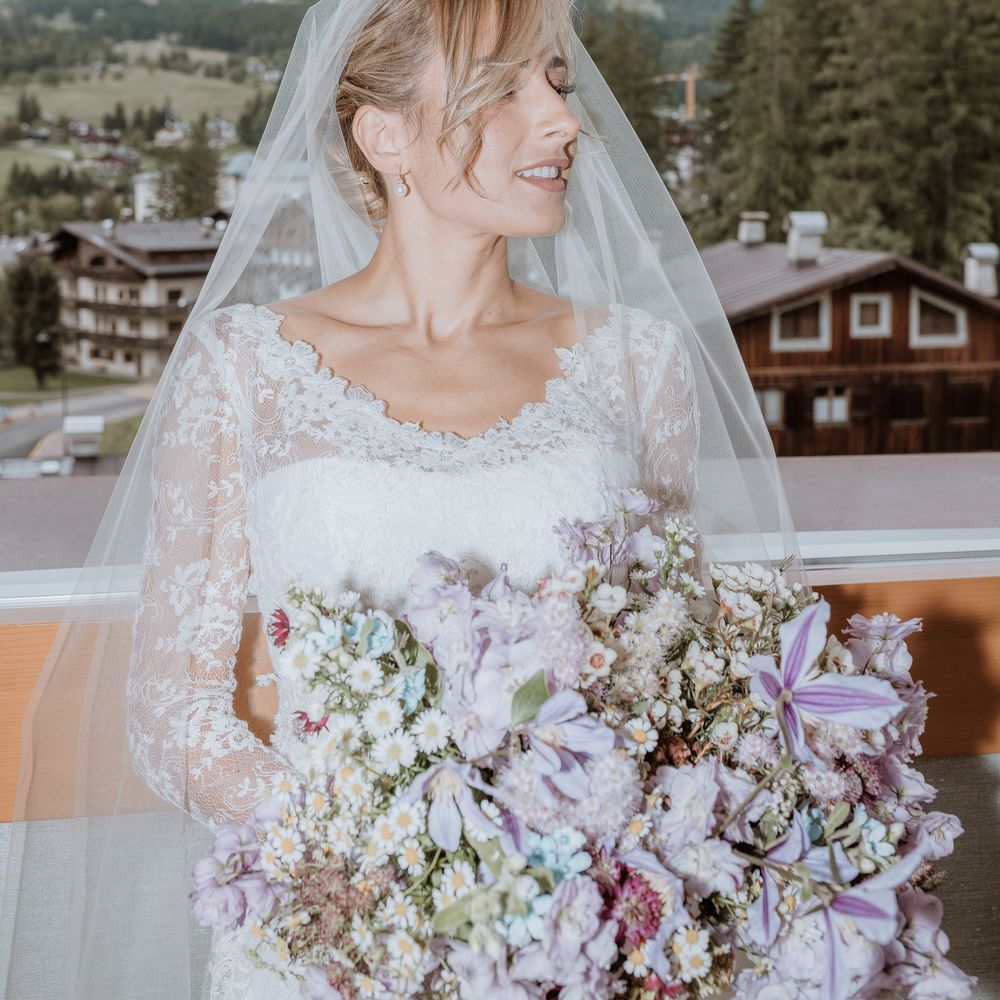 bride ready in front of dolomites snowy landscape lavender and daisy bouquet 