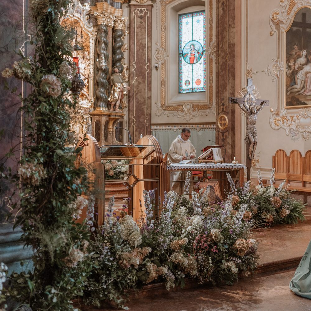 golden indoor church ceremony with forest green botanical decor