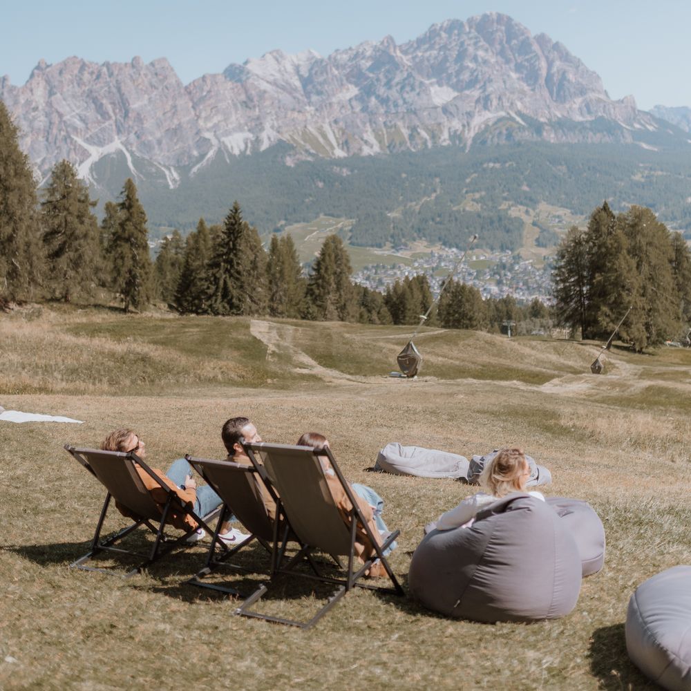 guests relaxing on deck chairs with italian dolomite mountain view