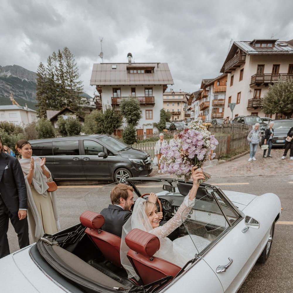 married couple leaving ceremony in white vintage car