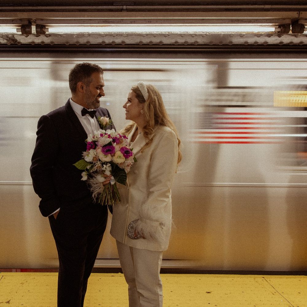 bride and groom in new york subway with train going past