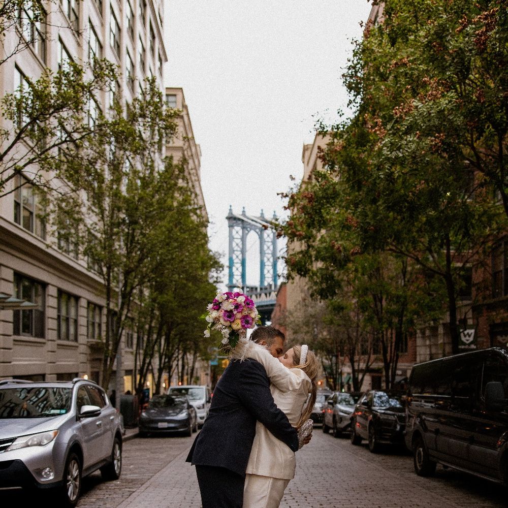 bride in white feather trim suit kissing groom in new york street