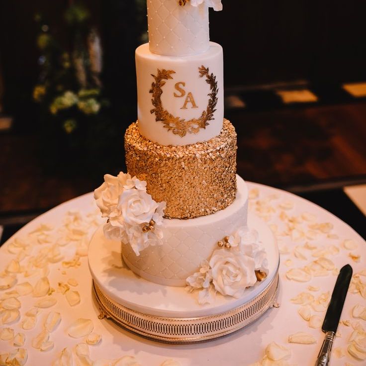 Four tier luxe iced wedding cake with gold metallic details and white flowers