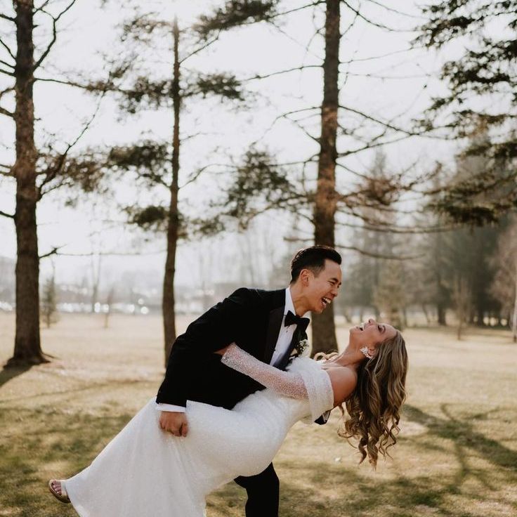 Groom sweeps bride for romantic couple portrait as she laughs