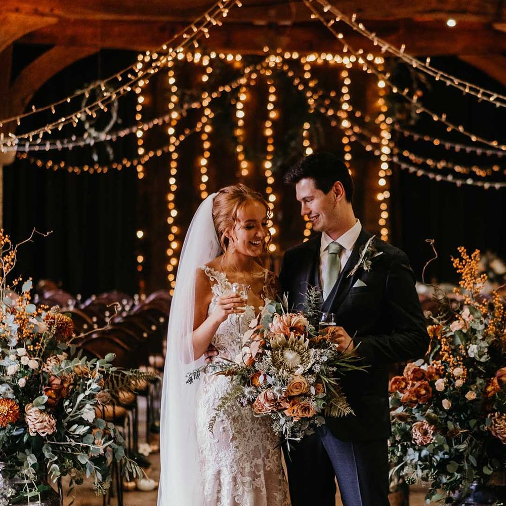 Bride and groom smiling at each other with fairy light backdrop