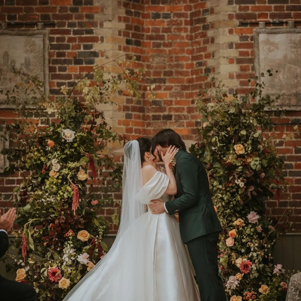 autumnal-wedding-flower-columns-as-couple-have-first-kiss