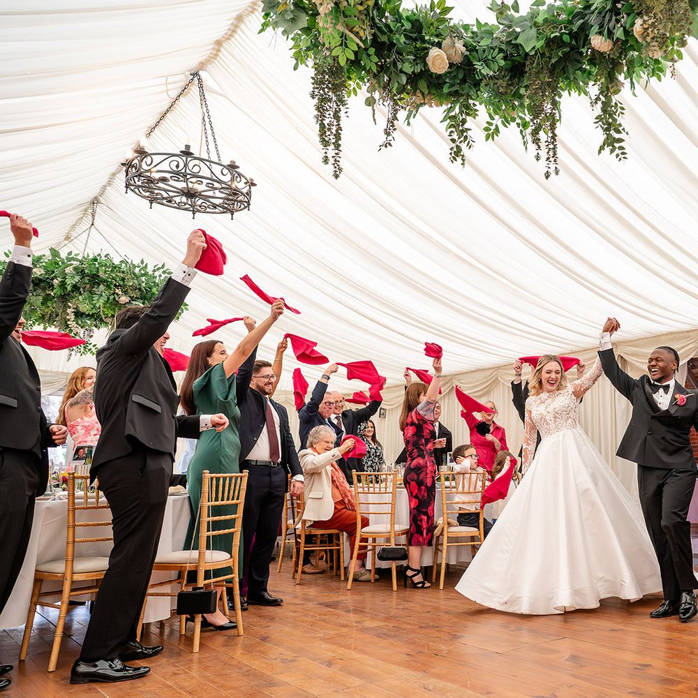 Chenies Manor marquee wedding red napkin wave entrance