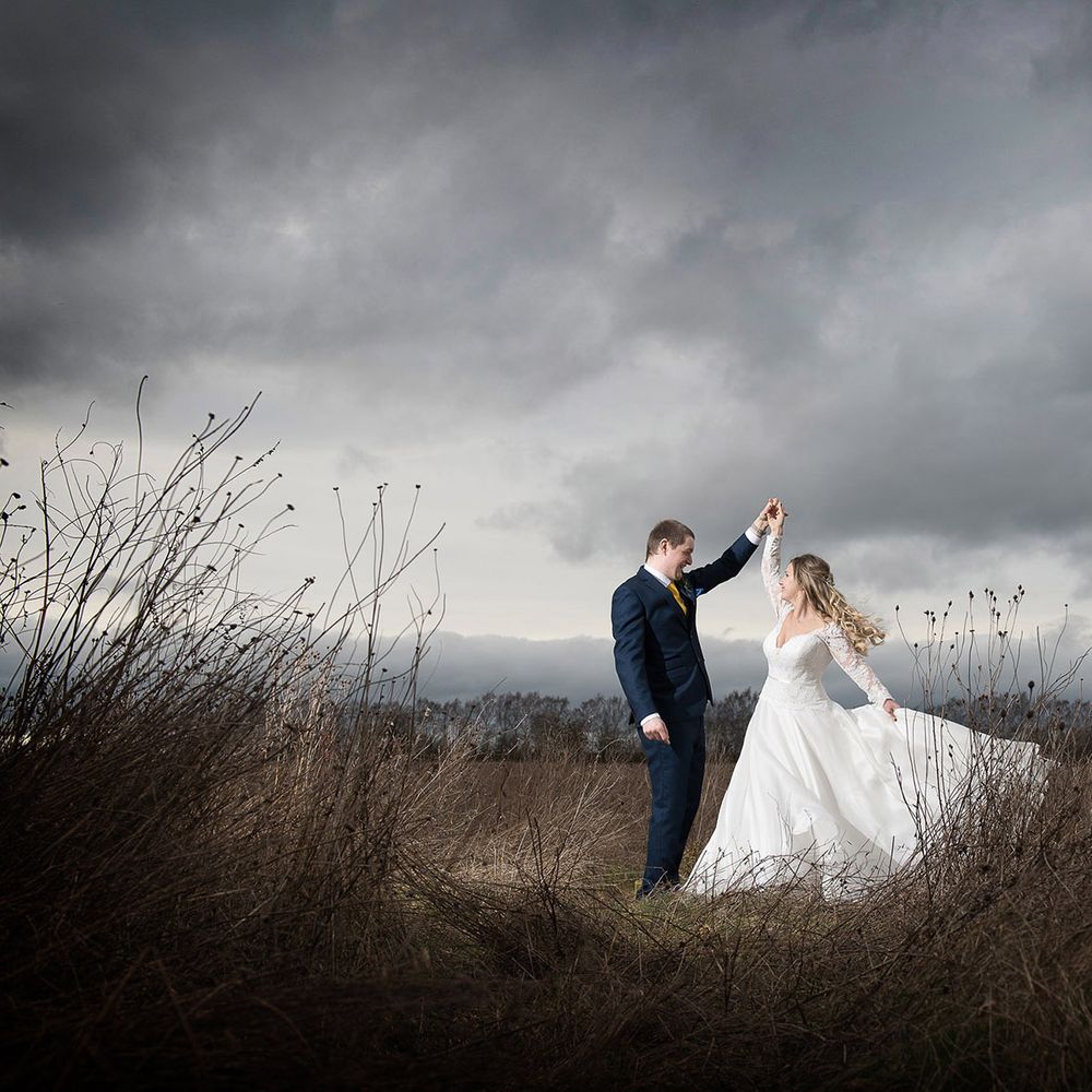bride and groom dancing in gloomy field 