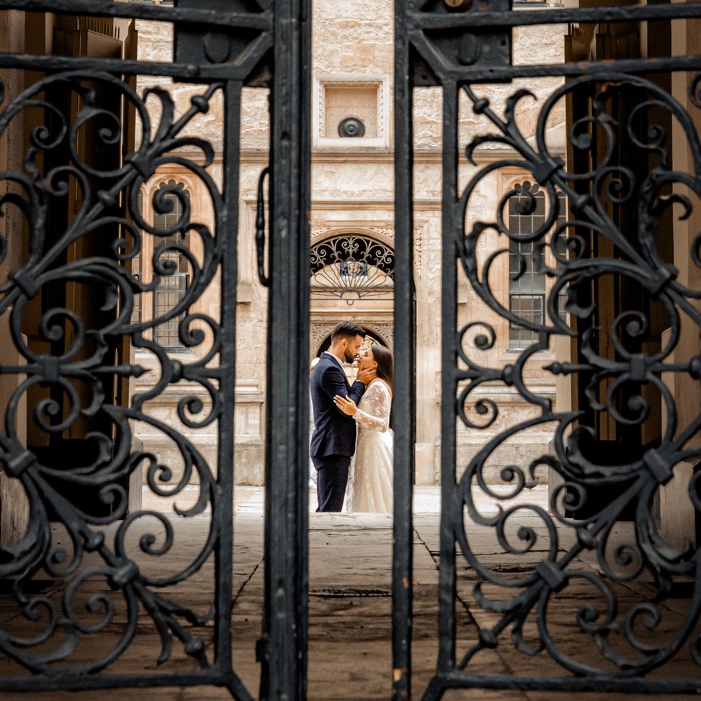 bride and groom embrace through black metal gates