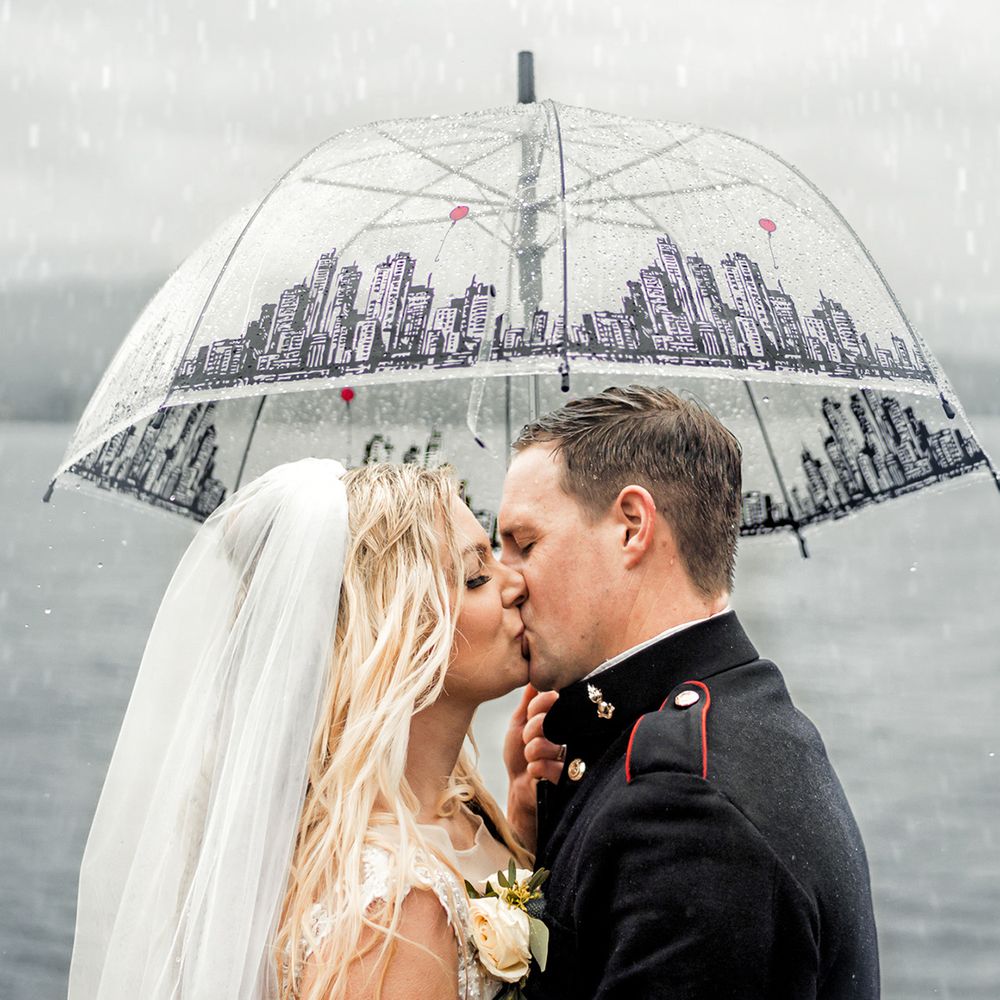 bride and groom kissing in rain under umbrella