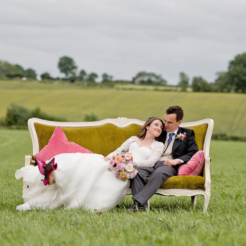 bride and groom on vintage sofa in grass fields