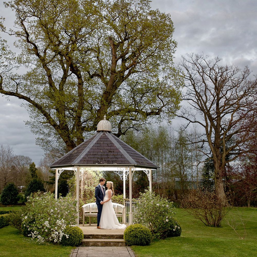 bride and groom under countryside bandstand