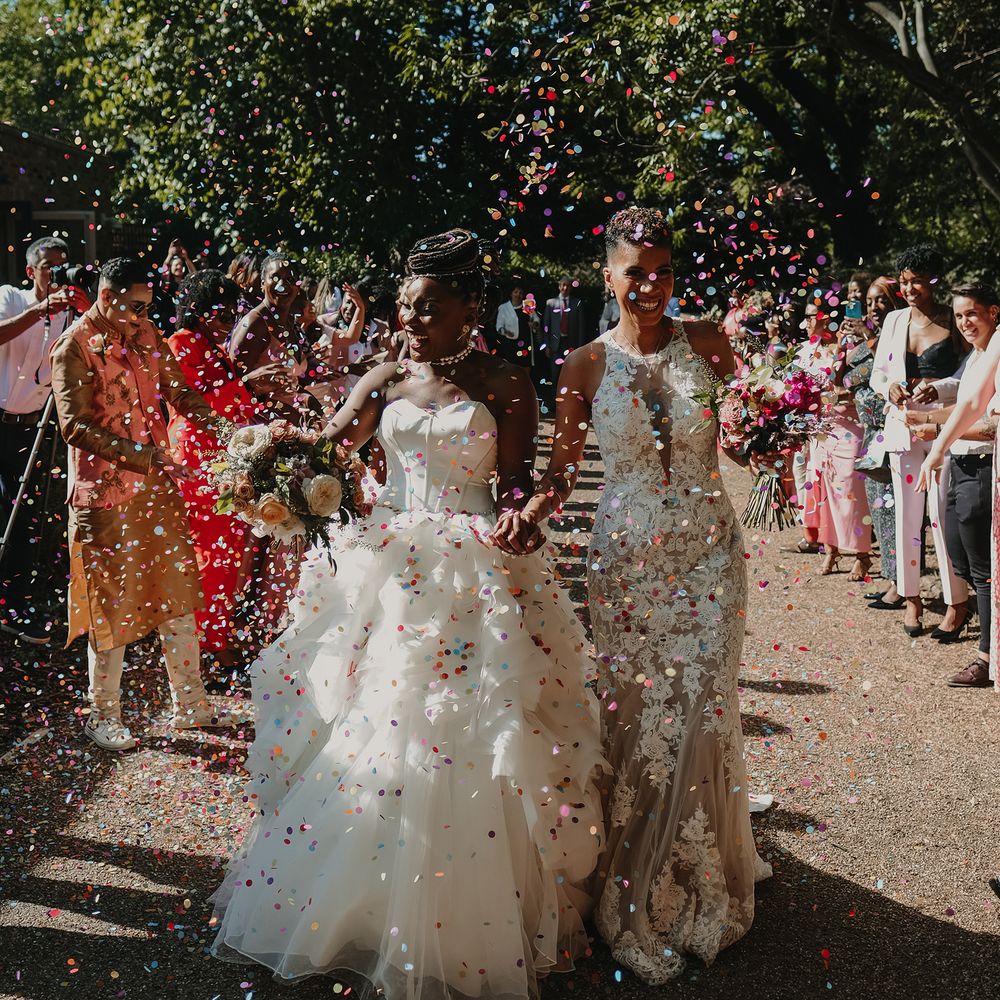 brides outdoor confetti walk smiling holding hands