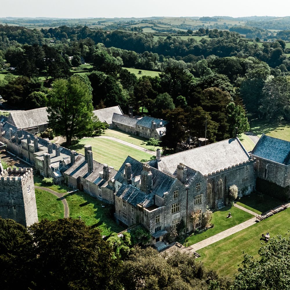 Aerial view of a historic stone castle with a tower, set amid rolling green countryside