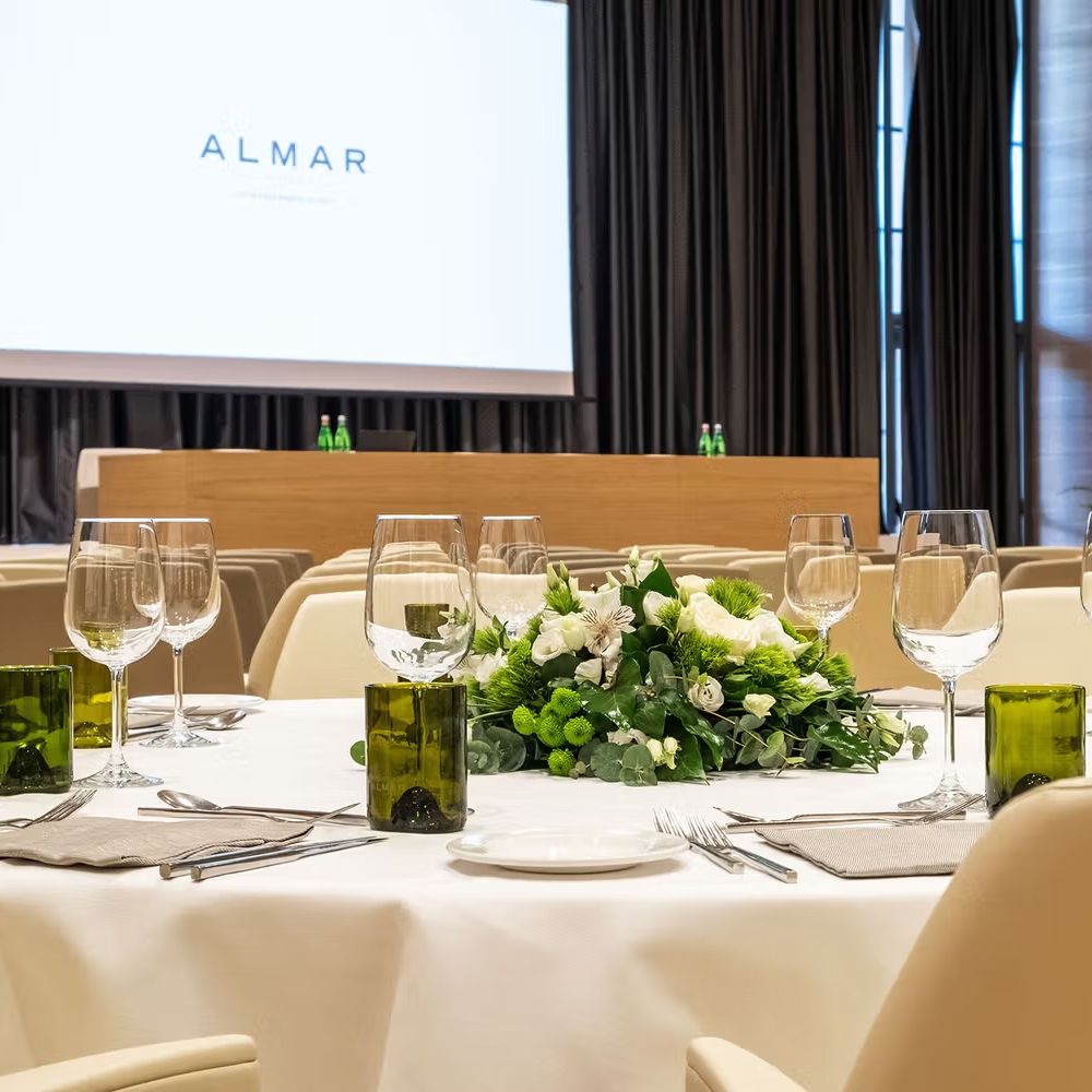 Round banquet table set with wine glasses and a white and green floral centrepiece in a conference room