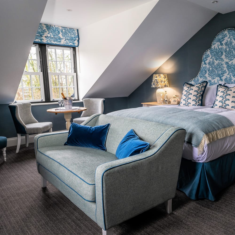 Blue bridal suite with patterned headboard, velvet cushions and champagne on ice by the window