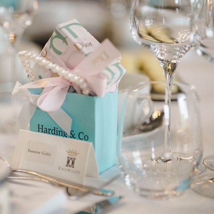 Duck egg blue favour bag tied with a pink bow beside a place card on an elegant table setting