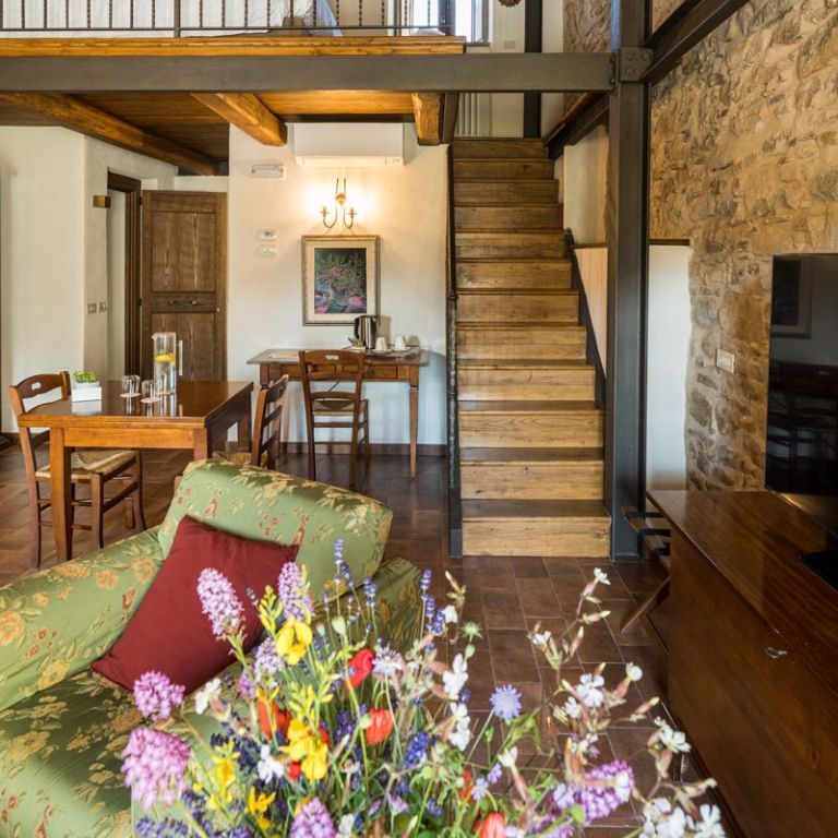 Rustic mezzanine suite with exposed beams, stone wall, wooden staircase and wildflower posy