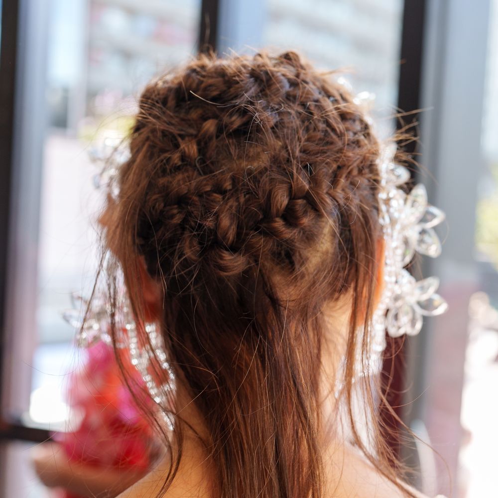 Rear view of a braided bridal updo adorned with crystal floral hairpieces and beaded straps