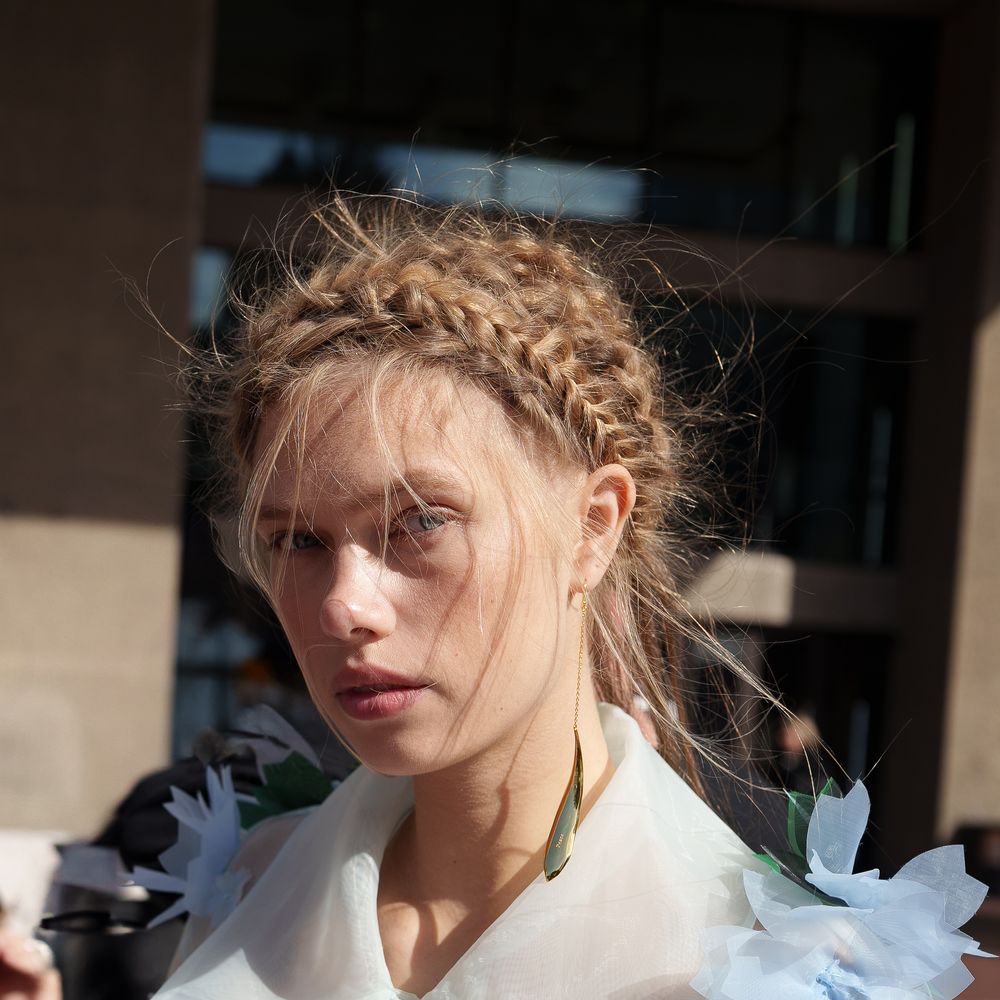 Bride with braided updo wearing sheer organza dress adorned with blue floral appliqués