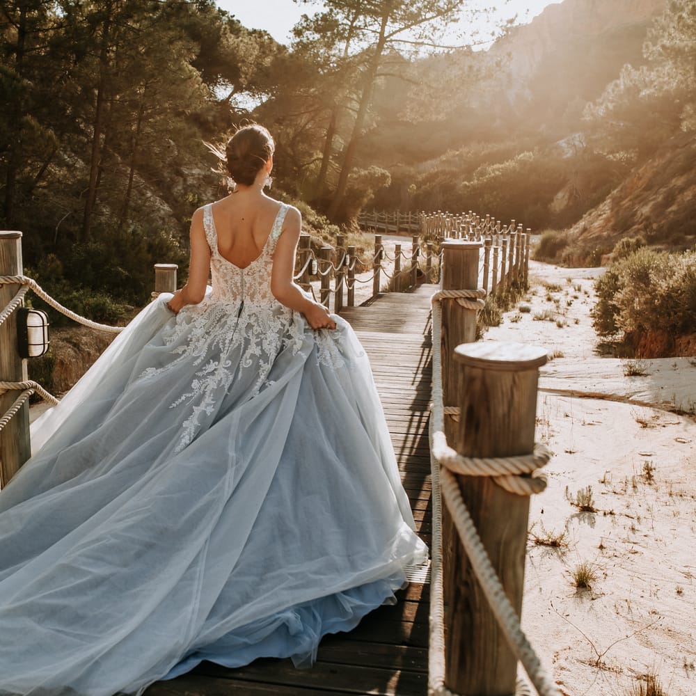 Bride in blue tulle gown walking along a wooden boardwalk at golden hour